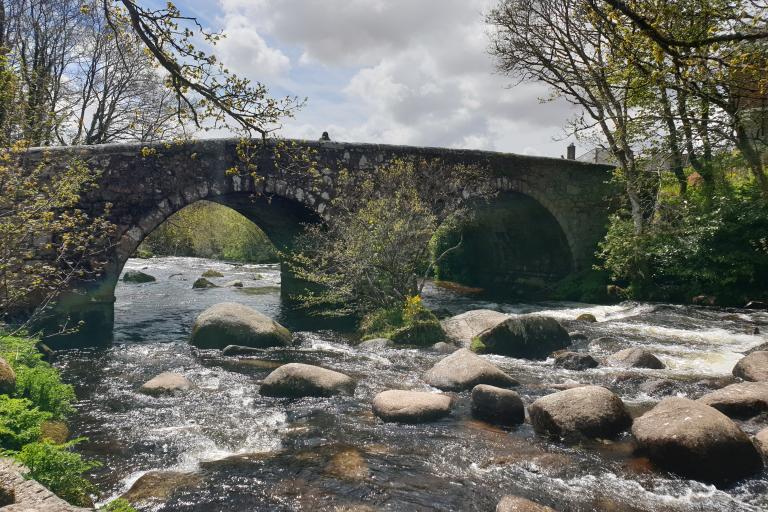 A photograph showing a stone  arch bridge spanning the river Dart, near to where it rises on Dartmoor.